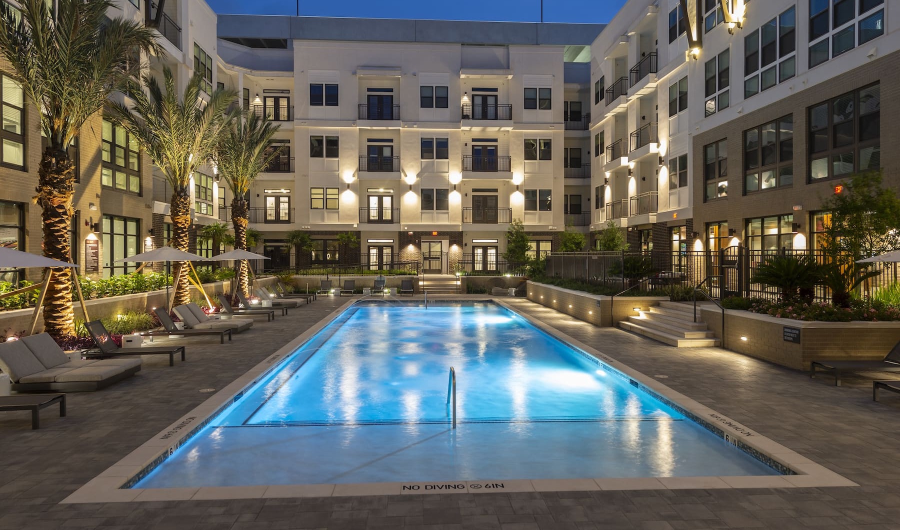 Lavish Amenities Large sparkling blue pool with a large deck and lounge chairs